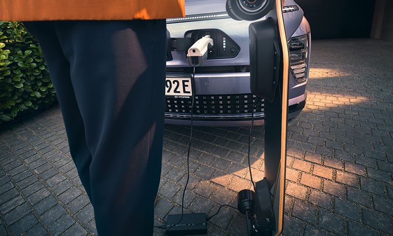 Met de Vehicle-to-Load-functie in de Hyundai KONA Electric kun je elektrische apparaten van stroom voorzien, zoals je elektrische skateboard.