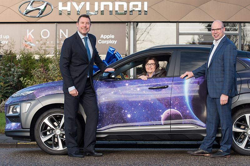 Jolanda van Orden de Graaf trots achter het stuur van haar Hyundai KONA, geflankeerd door Mike Belinfante van Hyundai Nederland (links) en Rob Knop van de Van der Linden Groep Waddinxveen.